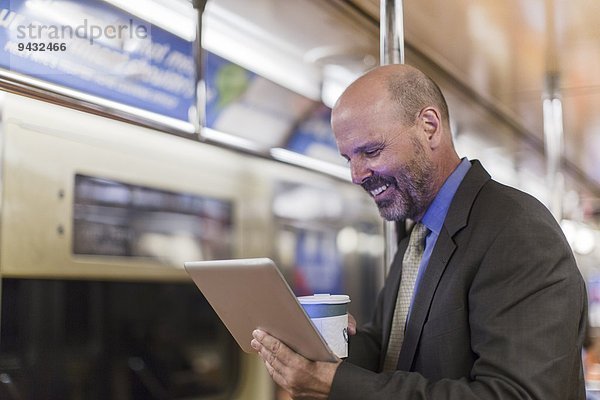 Erwachsener Mann in der U-Bahn mit digitalem Tablett