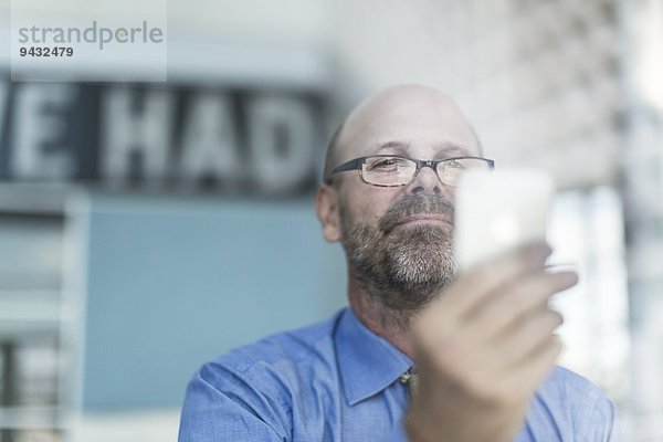 Erwachsener Geschäftsmann mit Brille per Handy