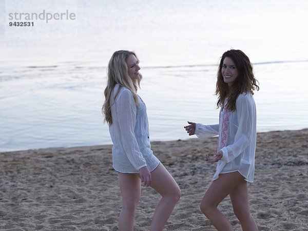 Zwei junge Freundinnen  die in der Abenddämmerung am Strand stehen  Williamstown  Melbourne  Australien