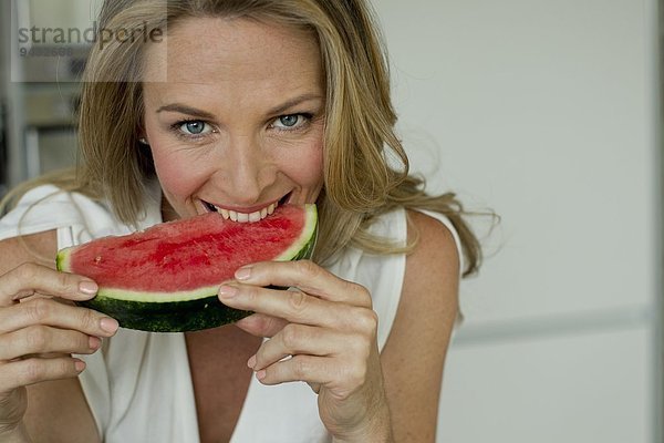 Reife Frau beißt Wassermelone