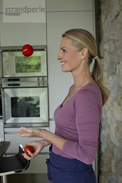 Reife Frau jongliert mit Tomaten