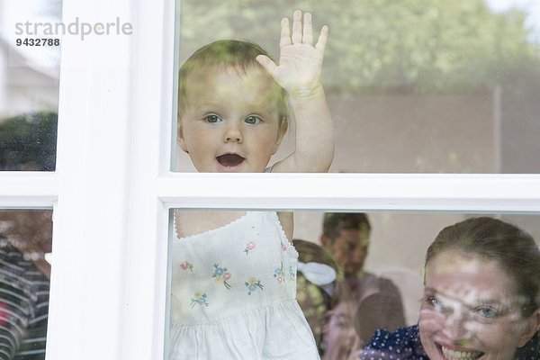 Mädchen und Mutter schauen aus dem Fenster.