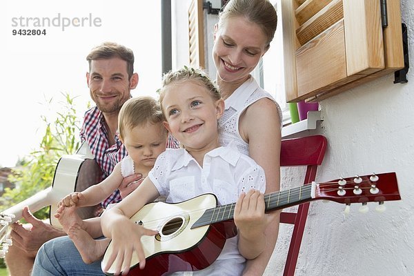 Mädchen spielt Gitarre mit Familie