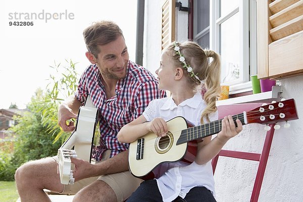 Mädchen spielt Gitarre mit Vater