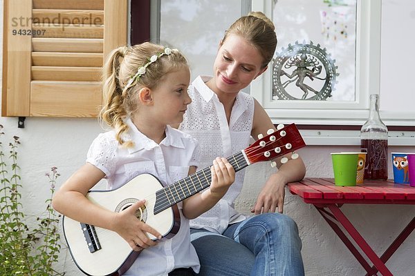 Mädchen spielt Gitarre mit Mutter