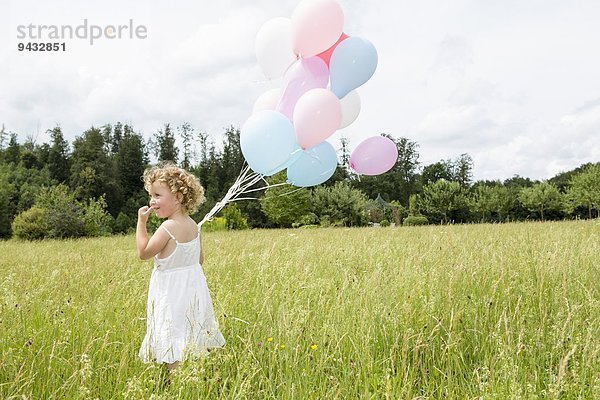 Junges Mädchen mit Luftballons im Feld