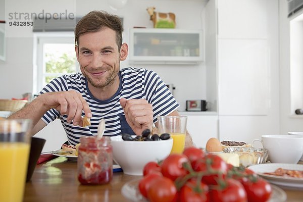 Mittlerer Erwachsener Mann beim Essen am Küchentisch