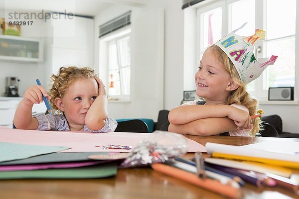 Zwei Mädchen am Tisch mit Papier und Bleistift