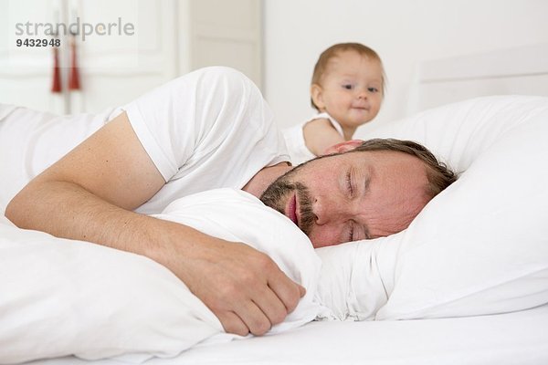 Vater schläft im Bett  Tochter schaut zu