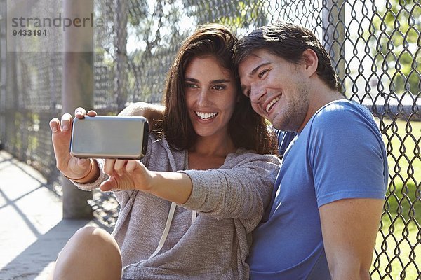 Junges Paar nimmt Selfie am Drahtzaun auf