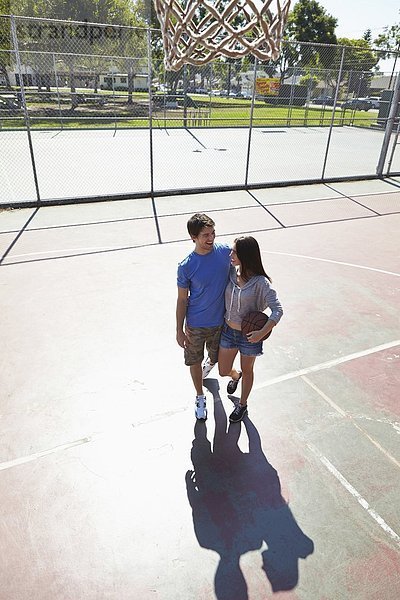 Junge Paare umarmen sich auf dem Basketballplatz