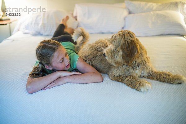 Junges Mädchen auf dem Bett neben dem Hund liegend