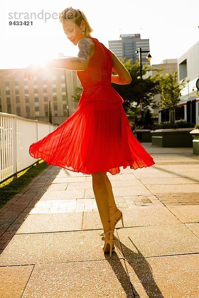 Junge Frau  die im roten Kleid wirbelt