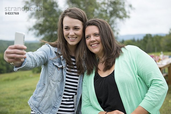 Zwei Freundinnen beim Selbstporträt mit dem Smartphone im Freien
