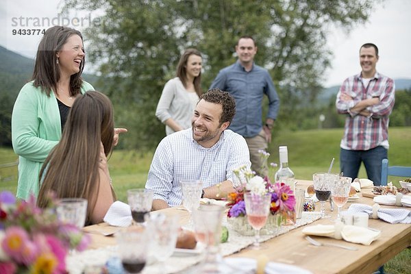 Familie und Freunde versammelten sich  unterhielten sich am Ende einer Mahlzeit im Freien.