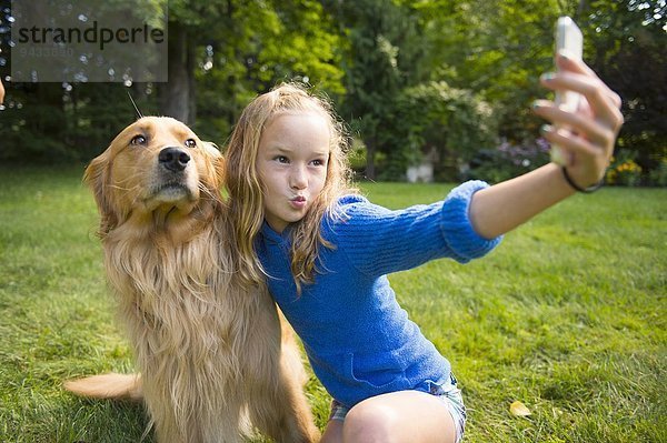 Mädchen nimmt Selfie mit Haustier Hund im Garten