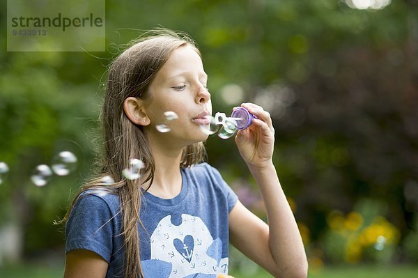 Mädchen bläst Blasen im Garten