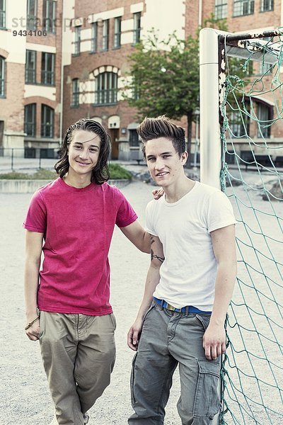 Portrait von selbstbewussten männlichen High-School-Freunden am Fußballnetz auf dem Schulhof