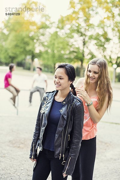 Highschool-Schüler flechtet die Haare eines Freundes auf dem Schulhof.