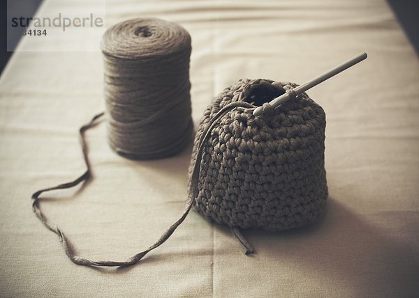 Halbfertige Wollhandtasche mit Spule auf dem Tisch