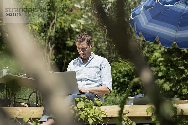 Mittlerer Erwachsener Mann mit Laptop auf der Terrasse