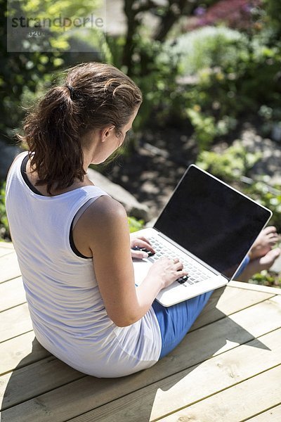 Hochwinkelansicht der mittleren erwachsenen Frau mit Laptop auf der Terrasse