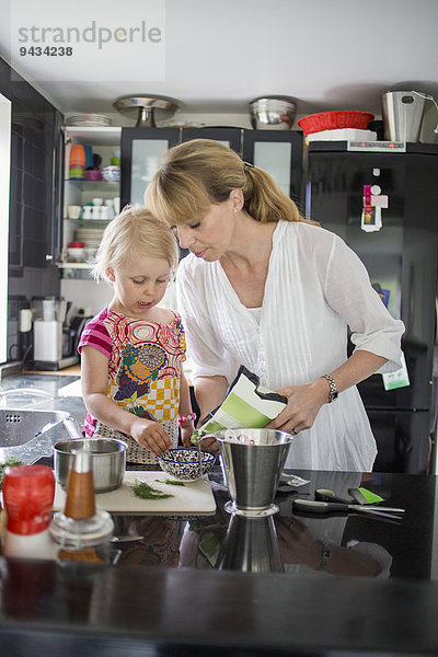 Mutter und Tochter bei der Zubereitung von Speisen in der Küche