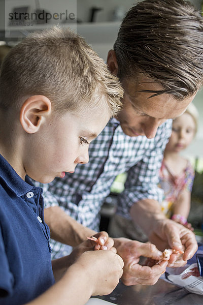 Vater und Sohn putzen Garnelen in der Küche