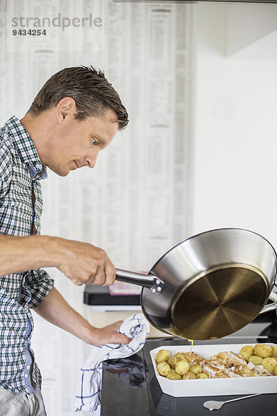 Seitenansicht des Mannes bei der Zubereitung von Speisen in der Küche