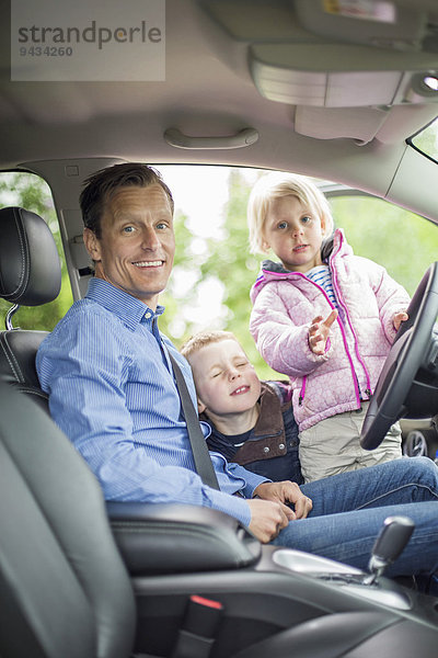 Porträt eines glücklichen Vaters mit Kindern im Auto