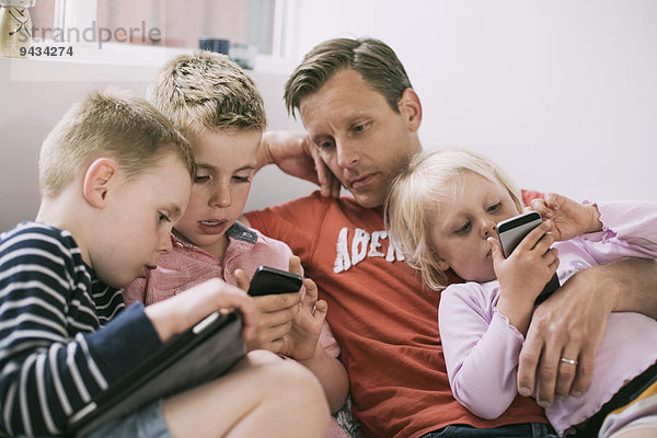 Vater und Kinder nutzen Technologien zu Hause