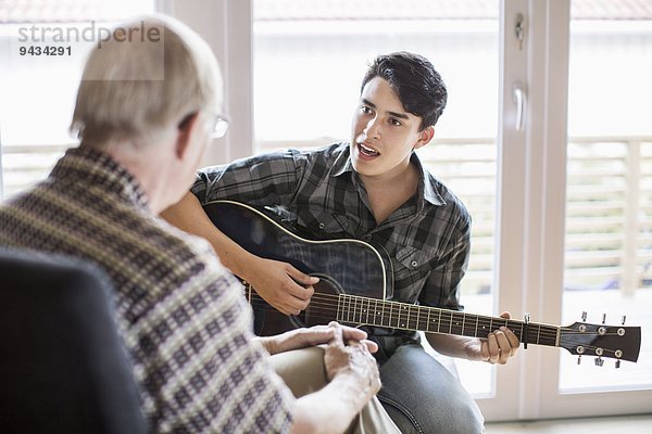 Enkel singen und Gitarre spielen für Großvater zu Hause