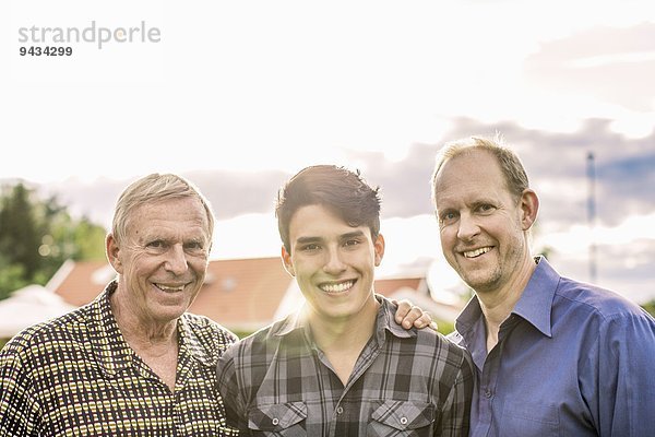 Porträt von drei Generationen männliche Familie lächelnd gegen den Himmel
