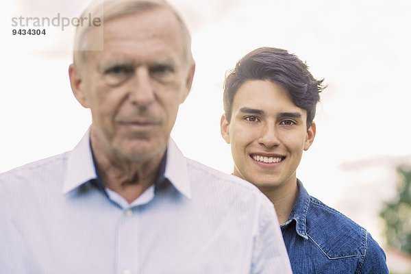 Porträt eines jungen Mannes  der mit Großvater im Vordergrund lächelt
