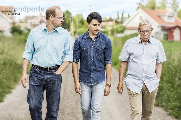 Drei Generationen von Männern  die zusammen auf einem Wanderweg gehen.