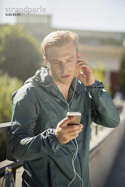 Fit Mann Musik hören durch Smartphone auf Brücke