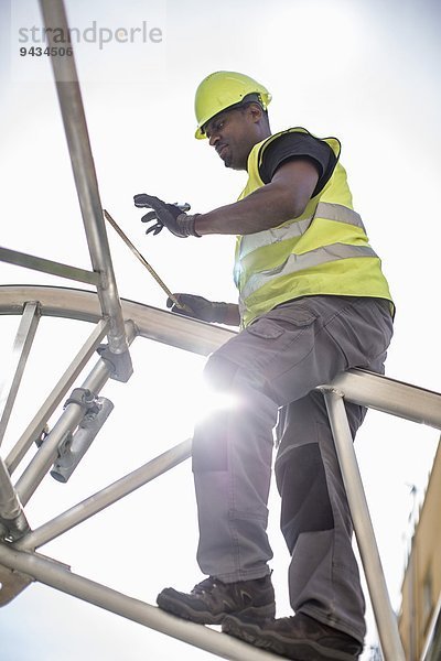 Niedriger Blickwinkel des Arbeiters auf den Baurahmen gegen den Himmel