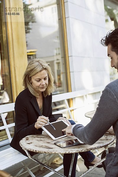 Geschäftskollegen mit digitalem Tablett im Straßencafé