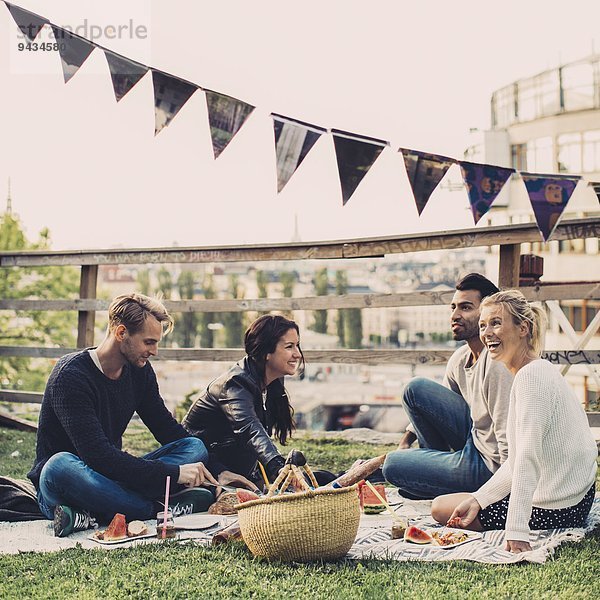 Glückliche Freunde beim Picknick auf dem Dachgarten