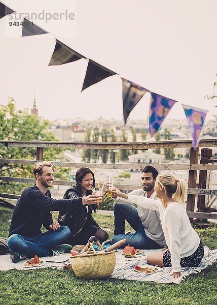 Multi-ethnische Freunde toasten Holunderblütengetränke auf der Dachparty