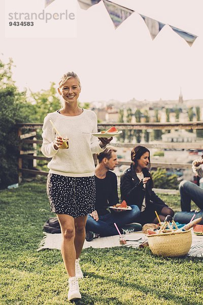 Porträt einer fröhlichen Frau mit Frühstück beim Spaziergang auf dem Dach der Wohnung