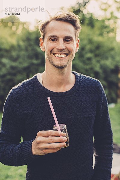 Porträt eines glücklichen Mannes mit Holunderblütengetränk auf dem Dachgarten