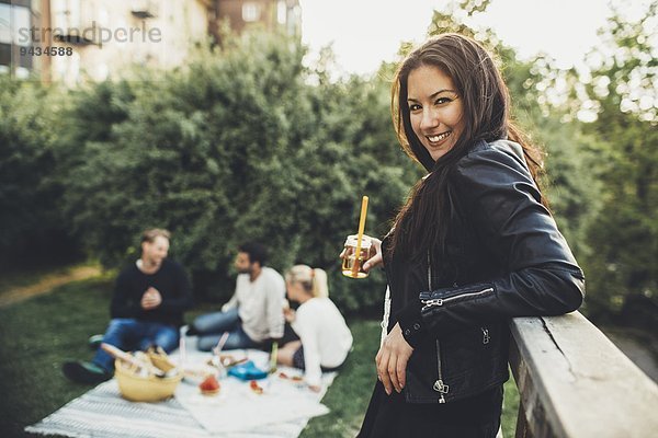 Seitenansicht Porträt einer glücklichen Frau mit Holunderblütengetränk während der Dachparty mit Freunden