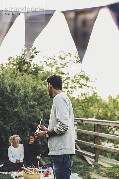 Mann schaut auf weibliche Freunde während der Dachparty