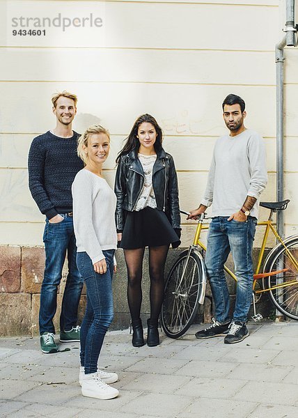 Ganzkörperporträt von Freunden  die mit dem Fahrrad auf dem Bürgersteig stehen