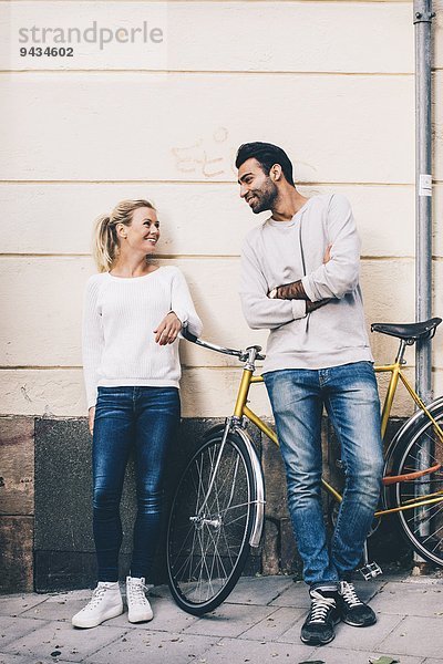 Freunde  die mit dem Fahrrad auf dem Bürgersteig stehen und miteinander kommunizieren.