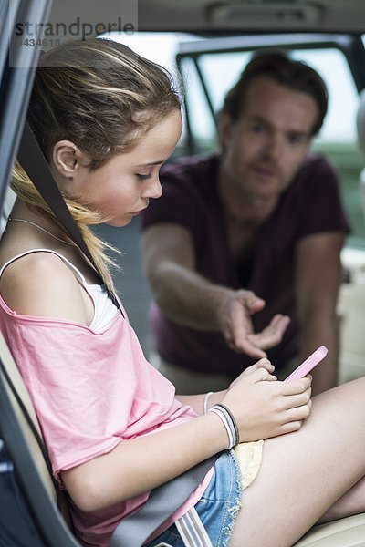 Tochter ignoriert Vater bei der Benutzung des Mobiltelefons im Auto