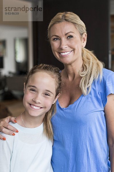 Porträt eines glücklichen Mädchens mit Mutter vor dem Haus stehend