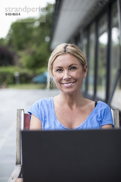 Porträt einer glücklichen Frau mit Laptop auf dem Hof