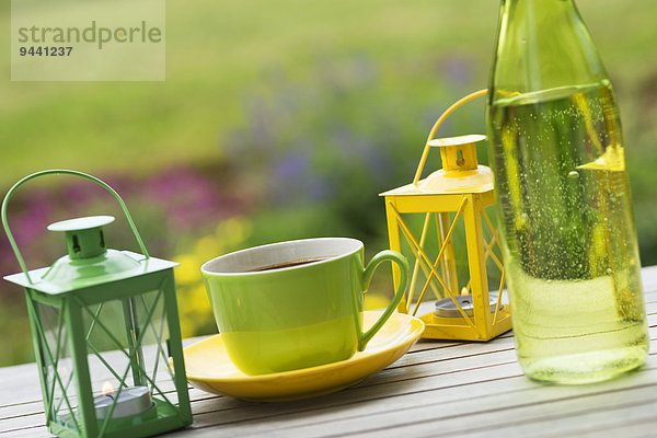 Gartentisch mit Kaffeetassen und Windlicht